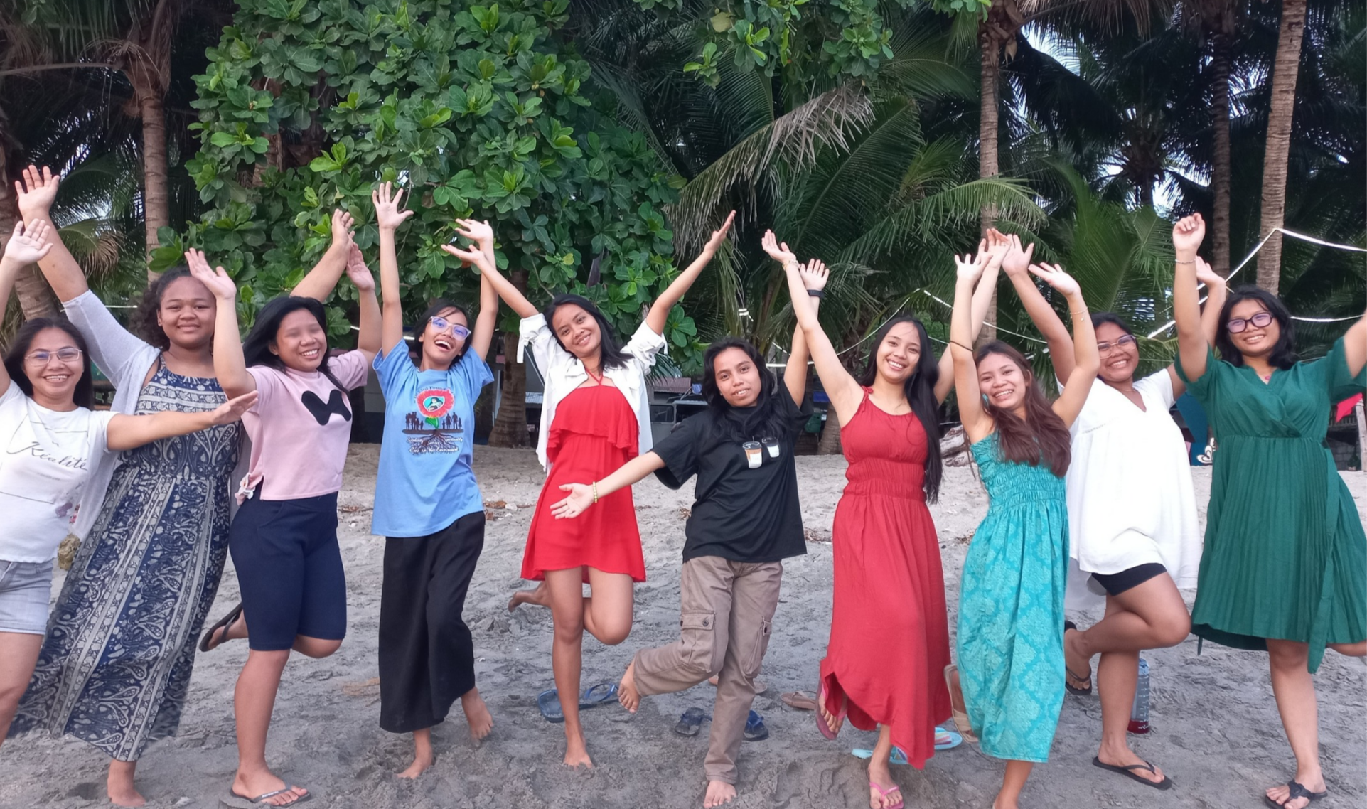Les jeunes filles de l'École de Vie, bras levés, sur la plage